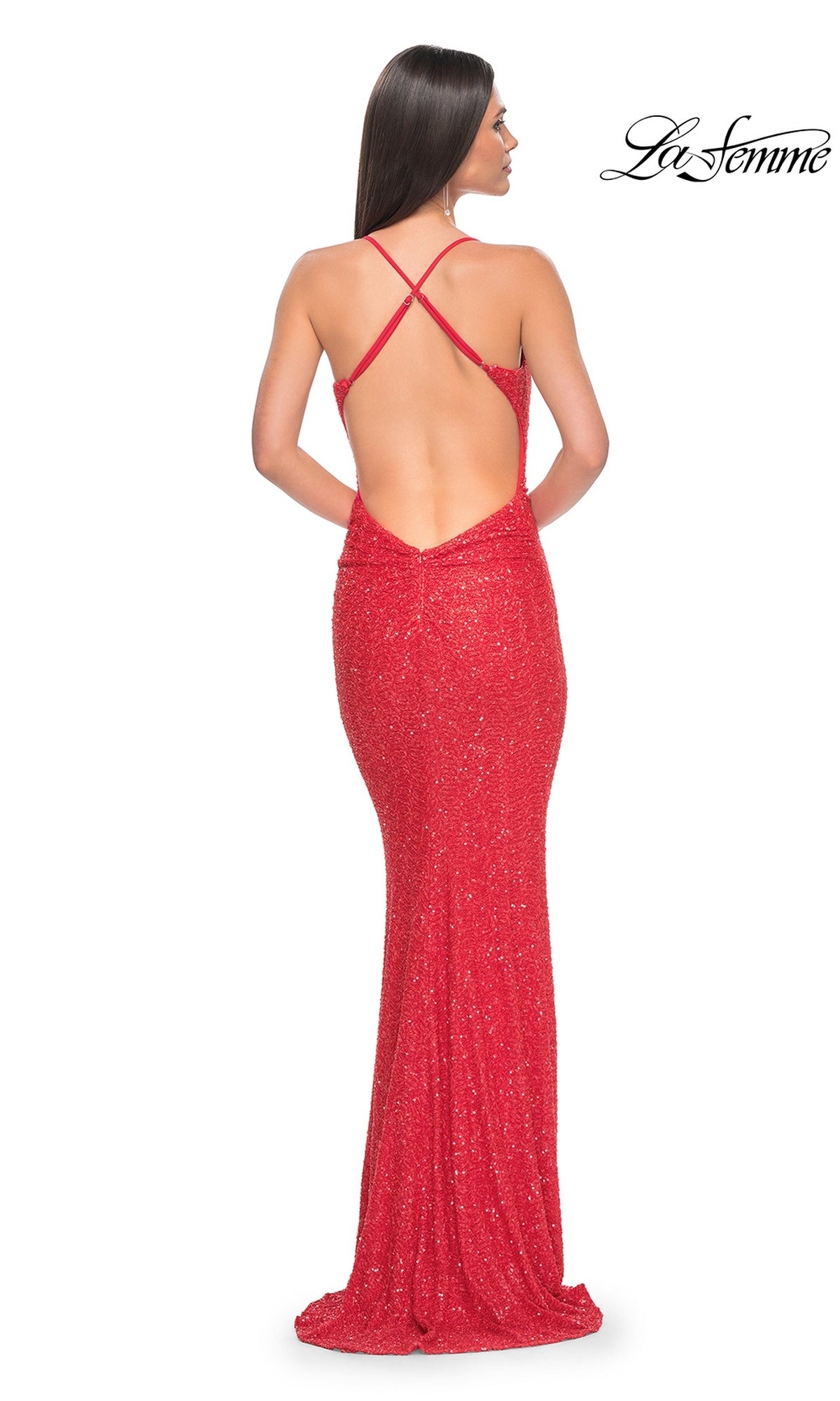 Woman in a floor-length, sparkly red La Femme Backless Long Sequin Prom Dress 31429 with an open crisscross back, standing against a white background.